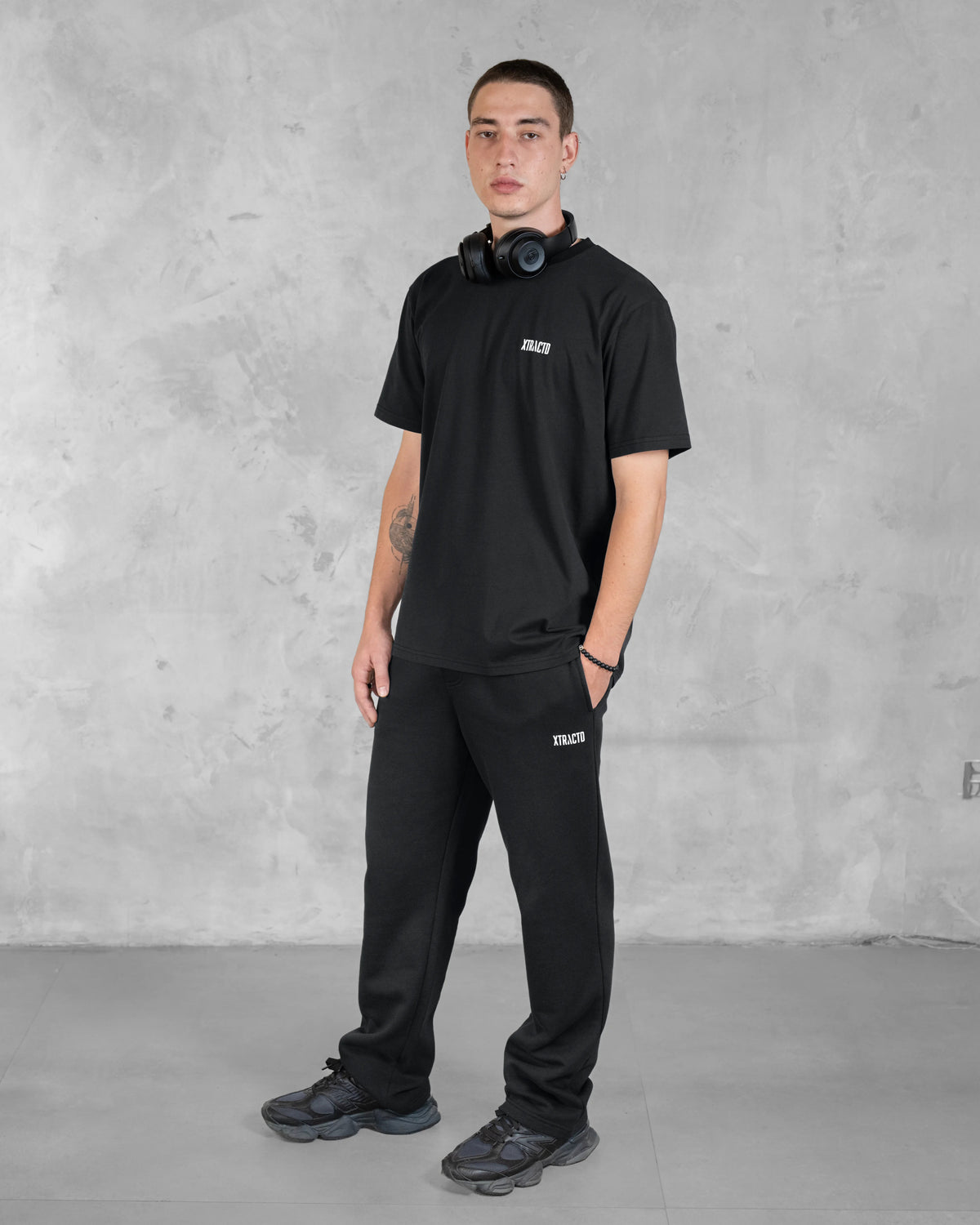 Model im schwarzen XTRACTD Basic T-Shirt und schwarzer Jogginghose, Ganzkörperansicht