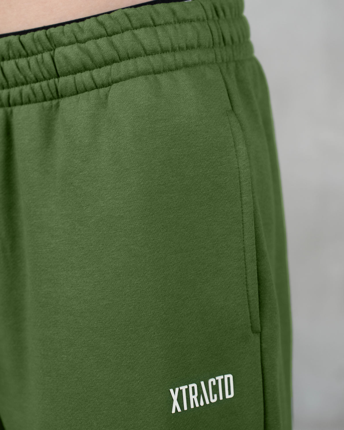 Detail der grünen XTRACTD Sweatpants Coffee Leaf mit XTRACTD-Schriftzug