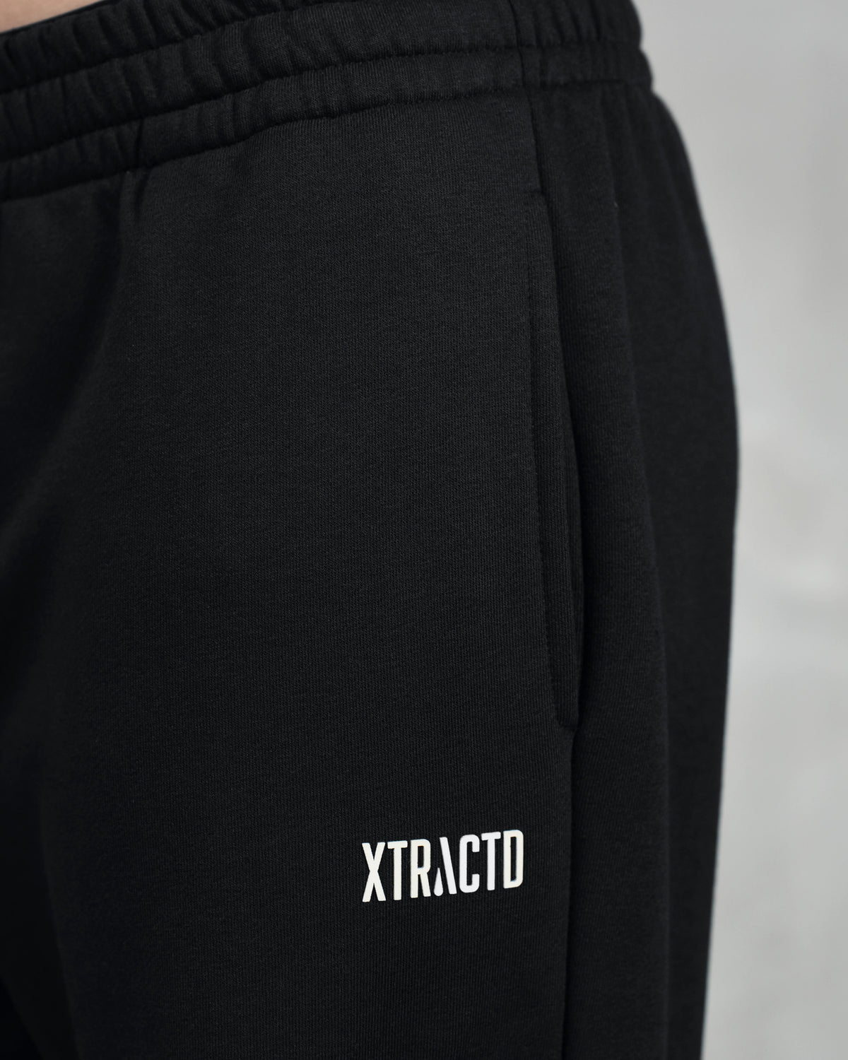 Detail der schwarzen XTRACTD Jogginghose mit weißem XTRACTD-Logo