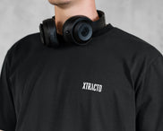 XTRACTD T-Shirt Rebellion in Espresso Black – Nahaufnahme des weißen Brust-Schriftzugs, Model mit Kopfhörern